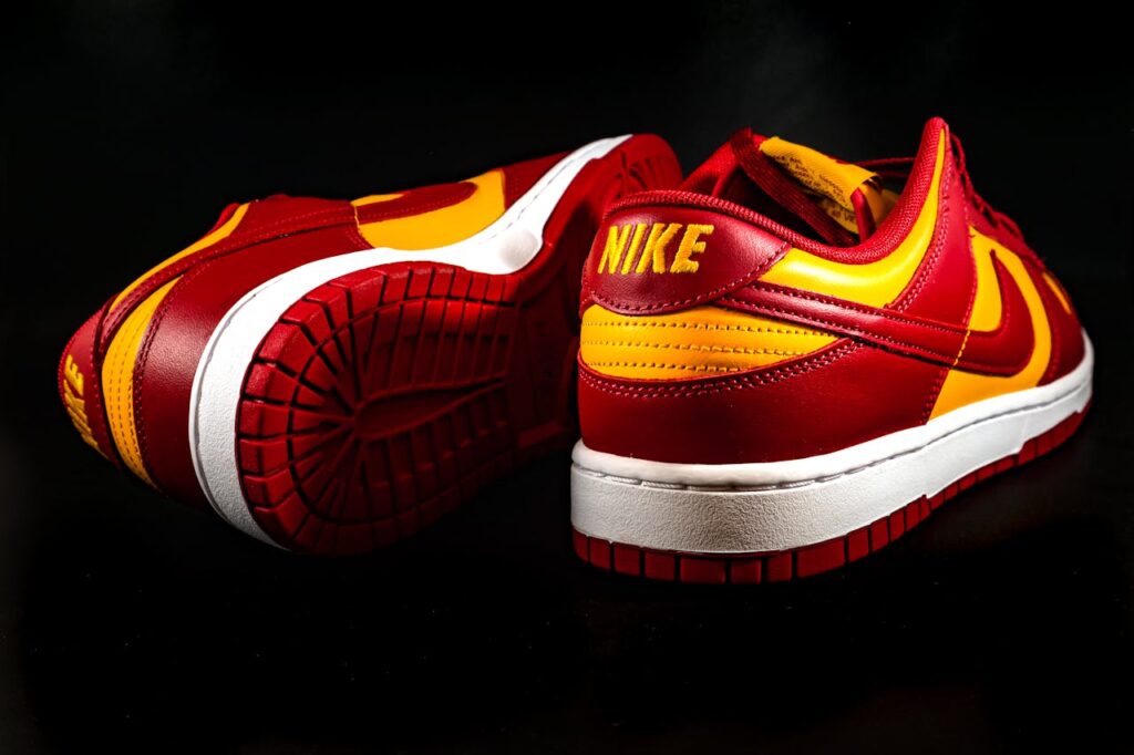 Red and yellow Nike sneakers displayed against a sleek black background, showcasing modern footwear design.